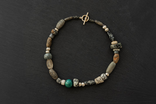 Ancient mali granite, ancient mali quartz, ethiopian metal and turquoise beaded necklace with a gold toggle clasp on a black background
